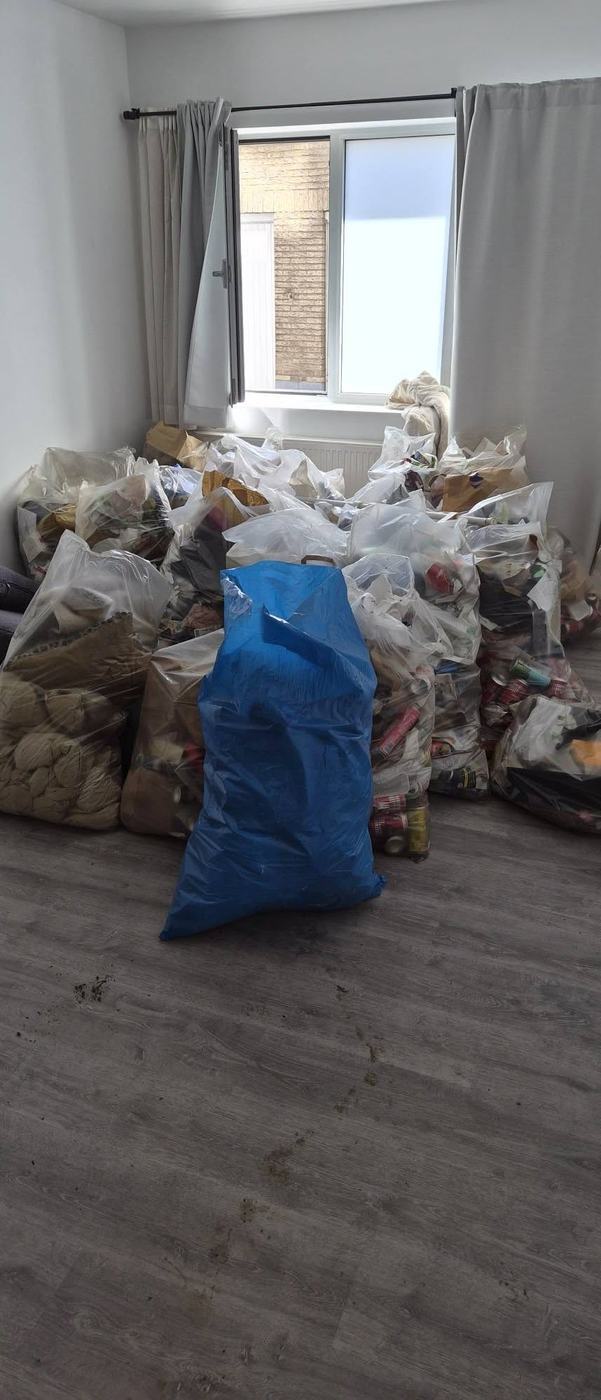 Kamer met tientallen gevulde afvalzakken opgestapeld voor het raam, klaar voor afvoer