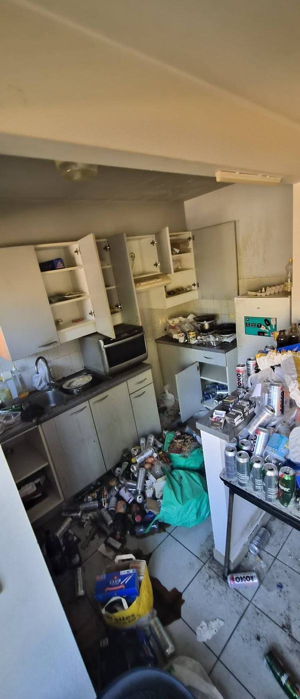 Zwaar vervuilde keuken met flessen, verpakkingen en huisraad tot tegen de kasten