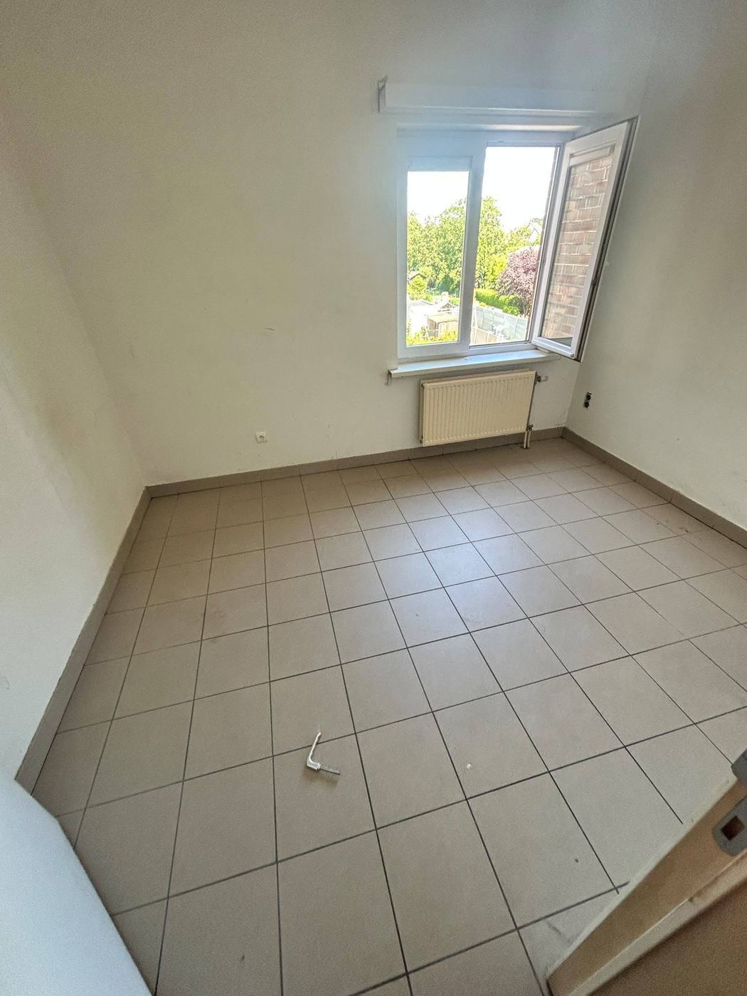 Leeggemaakte slaapkamer met gedweilde tegelvloer en een openstaand raam na de ontruiming